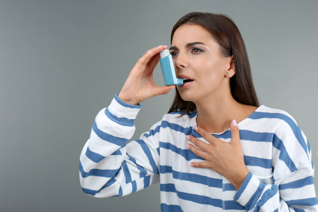 Fiatal nő segítségével asztma inhaláló, színes háttérrel - Fotó, kép