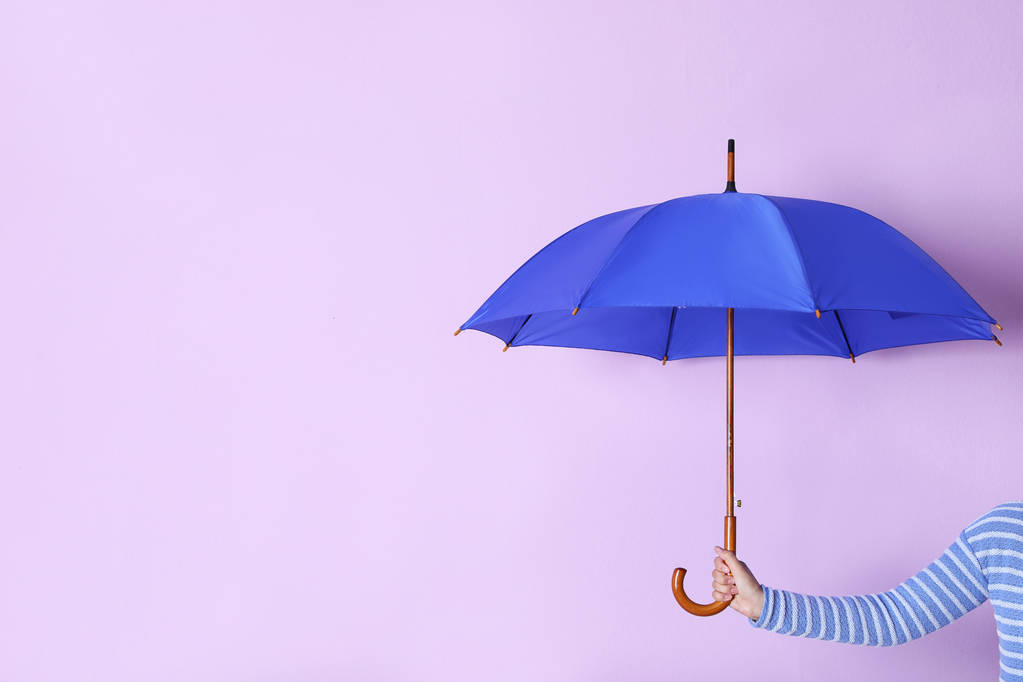 Человек держит яркий открытый зонтик на цветном фоне с пространством для дизайна
 - Фото, изображение