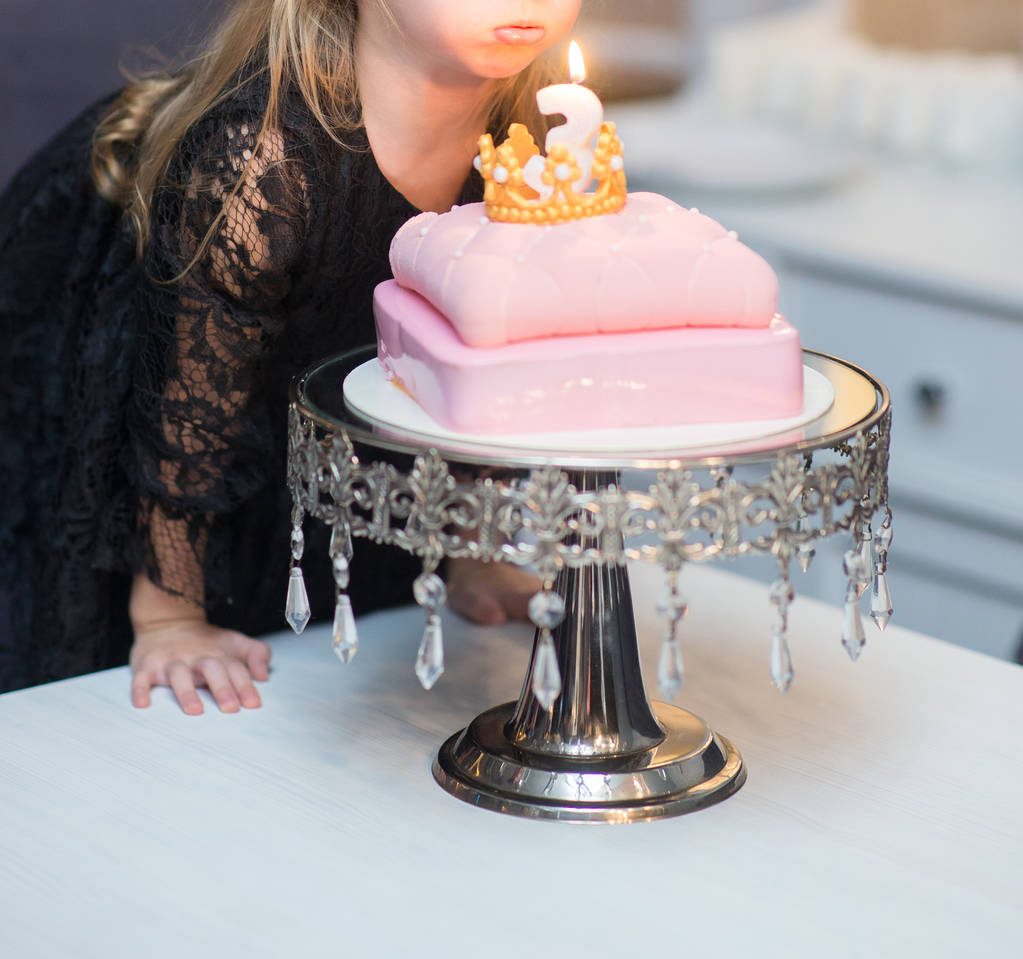 syntymäpäivä pieni tyttö puhaltaa kynttilän juhlava kakku vaaleanpunainen kerma
 - Valokuva, kuva