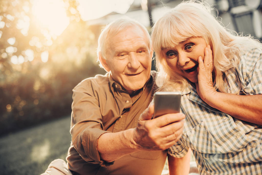 Couple aux cheveux gris regardant l'écran du smartphone
 - Photo, image