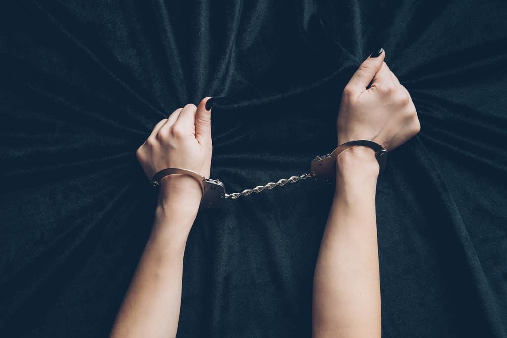 обрезанный снимок женских рук в наручниках с черной тканью
  - Фото, изображение