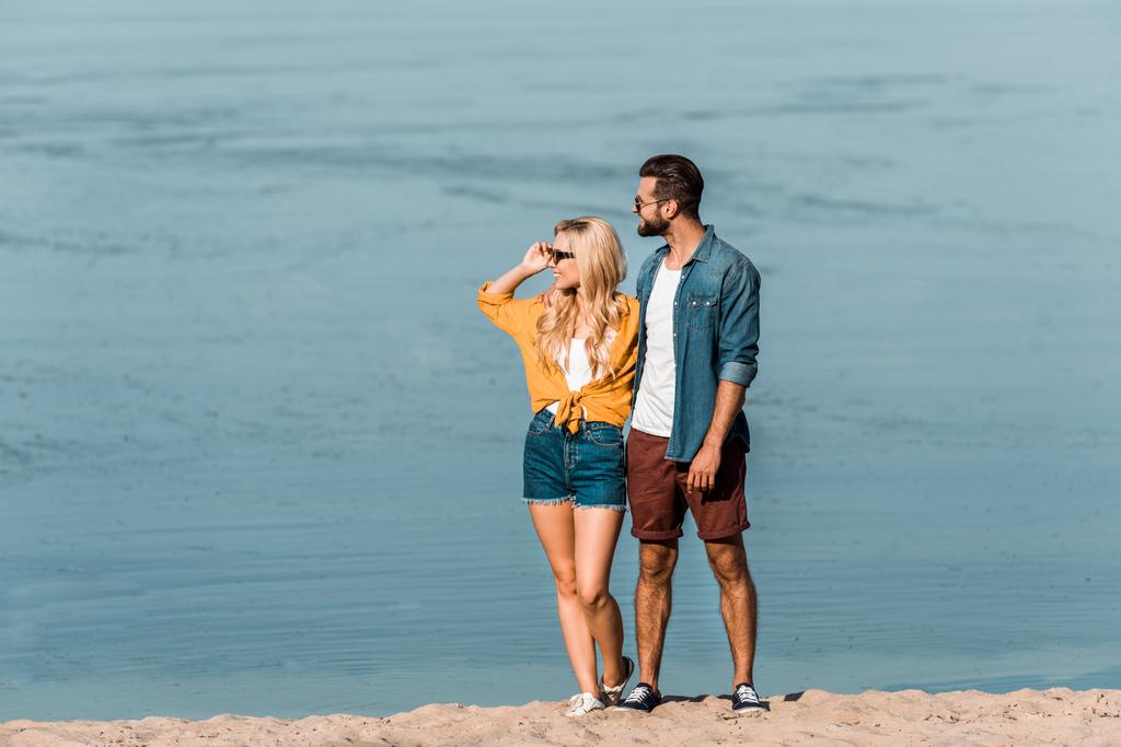 paar in casual kleding weg op zoek op strand - Foto, afbeelding