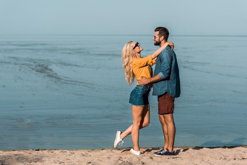 pari aurinkolasit halailevat ja katselevat toisiaan rannalla
  - Valokuva, kuva