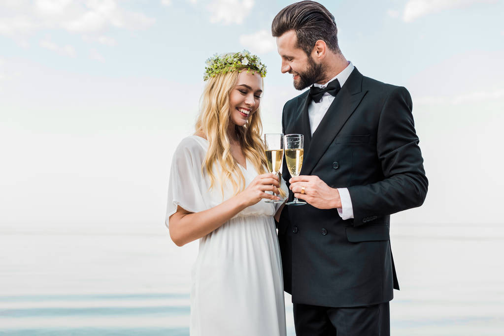 s úsměvem svatební pár cinkání sklenic šampaňského na pláži - Fotografie, Obrázek