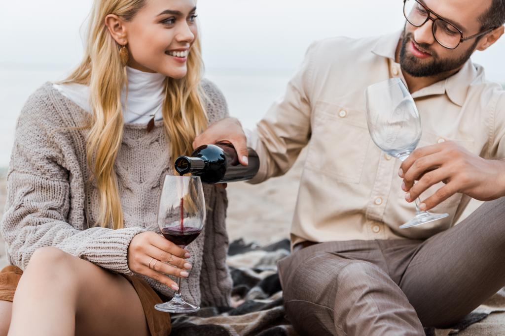 ο φίλος στο Φθινοπωρινό ντύσιμο έκχυση κόκκινο κρασί σε ποτήρια στην παραλία - Φωτογραφία, εικόνα
