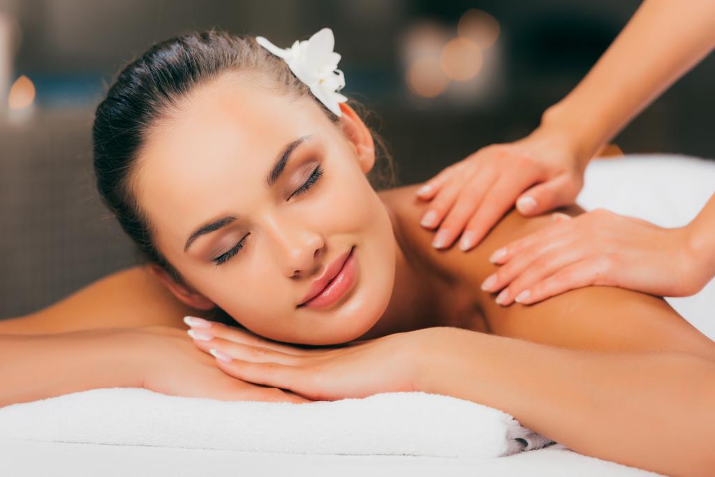 красива молода жінка з квіткою в волоссі, масаж в спа-салоні
  - Фото, зображення