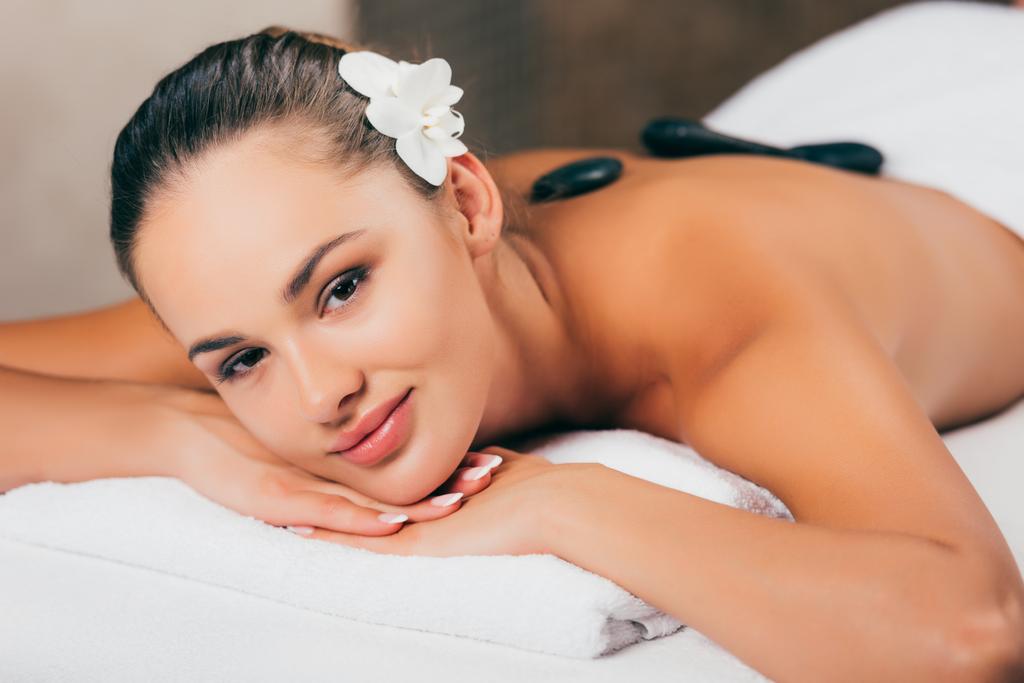uśmiechnięta kobieta o terapii kamienia w salonie spa - Zdjęcie, obraz