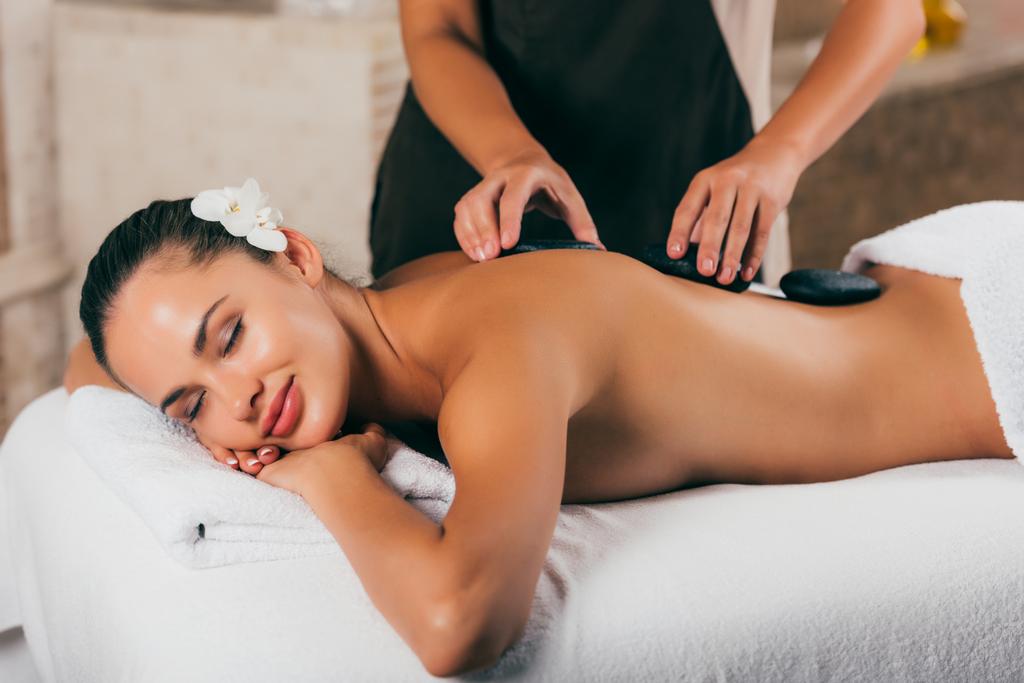 mujer joven teniendo terapia de piedra en el centro de spa
  - Foto, Imagen