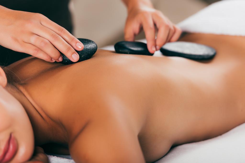 vue recadrée de la jeune femme ayant la thérapie de pierre au salon de massage
  - Photo, image