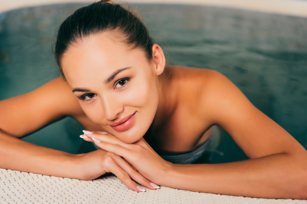женщина расслабляется в бассейне и смотрит в камеру
 - Фото, изображение