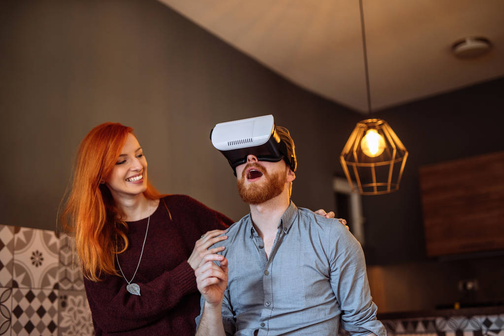 Girato di una giovane coppia felice che si gode a casa con auricolare realtà digitale
. - Foto, immagini