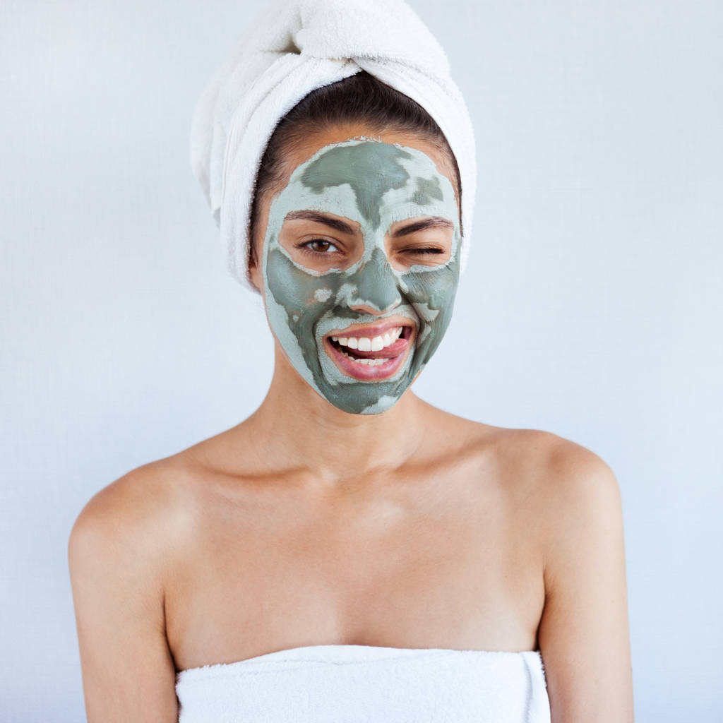 Giovane bella donna in maschera viso di fango terapeutico blu. Trattamento termale, cura di sé e pelle sana. Copia spazio, sfondo bianco - Foto, immagini