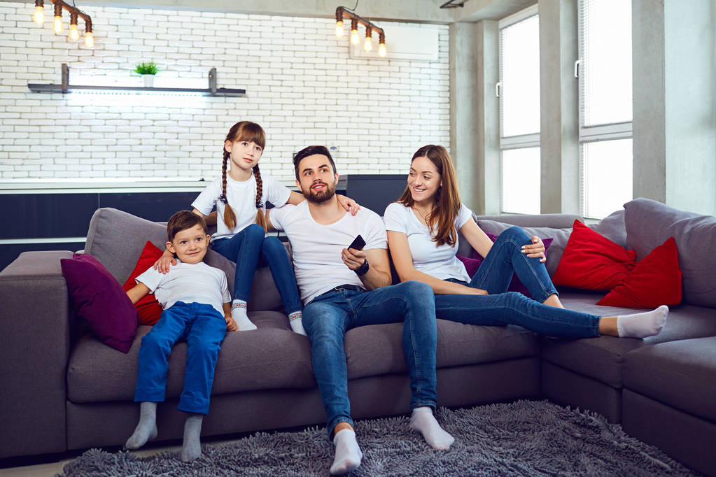 Una familia con un mando a distancia mira la televisión en la habitación
. - Foto, Imagen