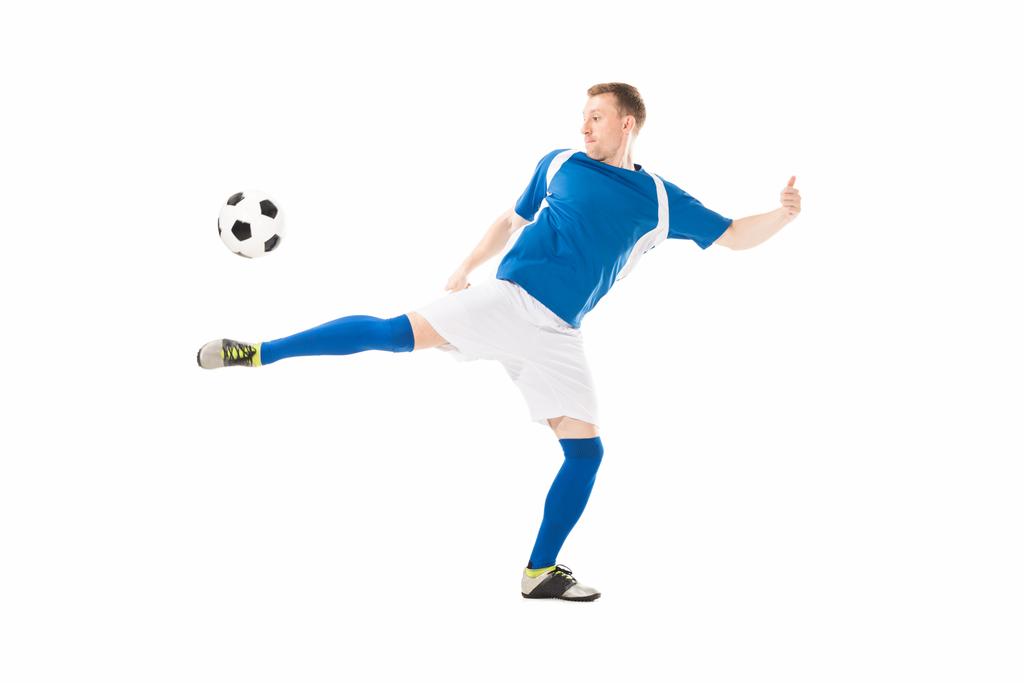 Widok pełnej długości lekkoatletycznego młody piłkarz kopie piłkę na białym tle - Zdjęcie, obraz