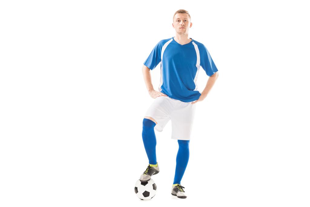 confiante jovem jogador de futebol de pé com as mãos nos quadris e olhando para a câmera isolada no branco
 - Foto, Imagem