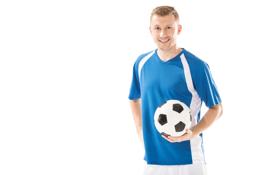 šťastný, mladý sportovec drží fotbalový míč a usmívá se na kameru izolované na bílém - Fotografie, Obrázek
