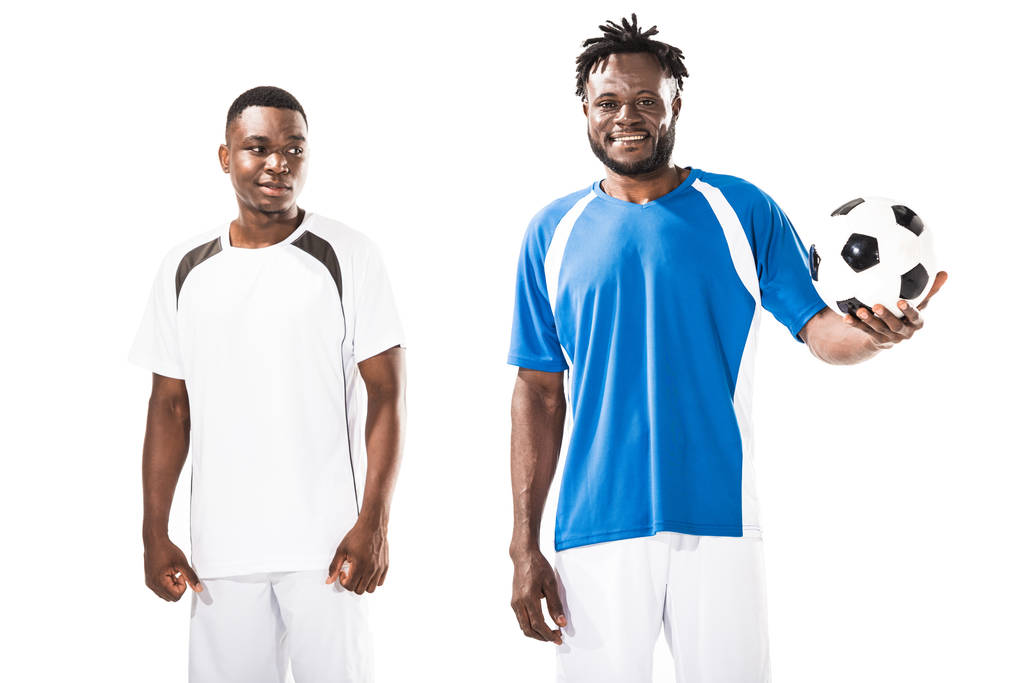 knappe lachende jonge Afro-Amerikaanse voetballers permanent met bal geïsoleerd op wit - Foto, afbeelding