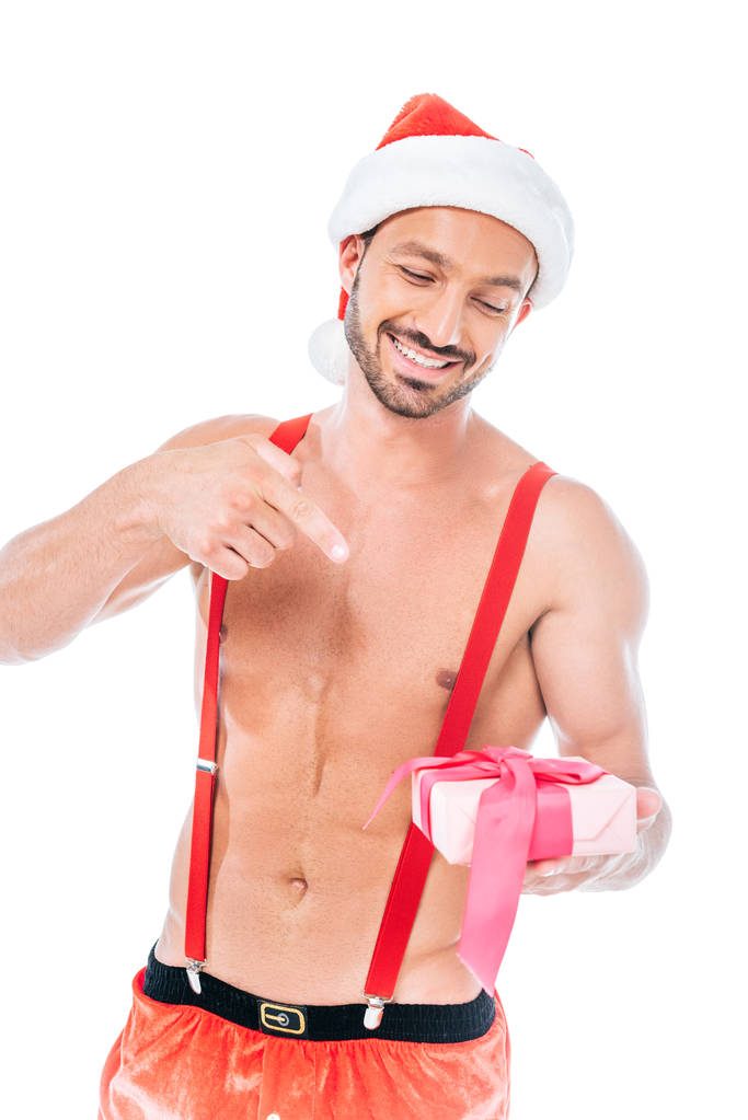 sorridente sem camisa muscular homem no chapéu de Natal apontando para caixa de presente isolado no fundo branco
 - Foto, Imagem