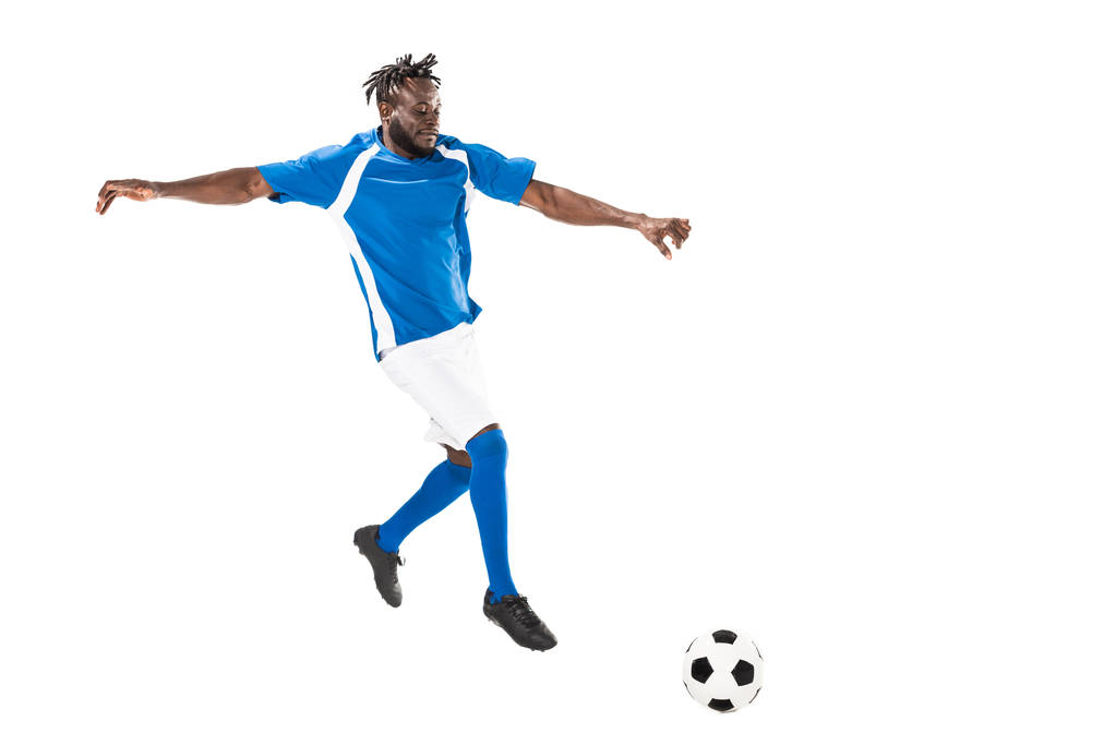 полный вид спортивного африканского футболиста, ударяющего по мячу, изолированному на белом
  - Фото, изображение