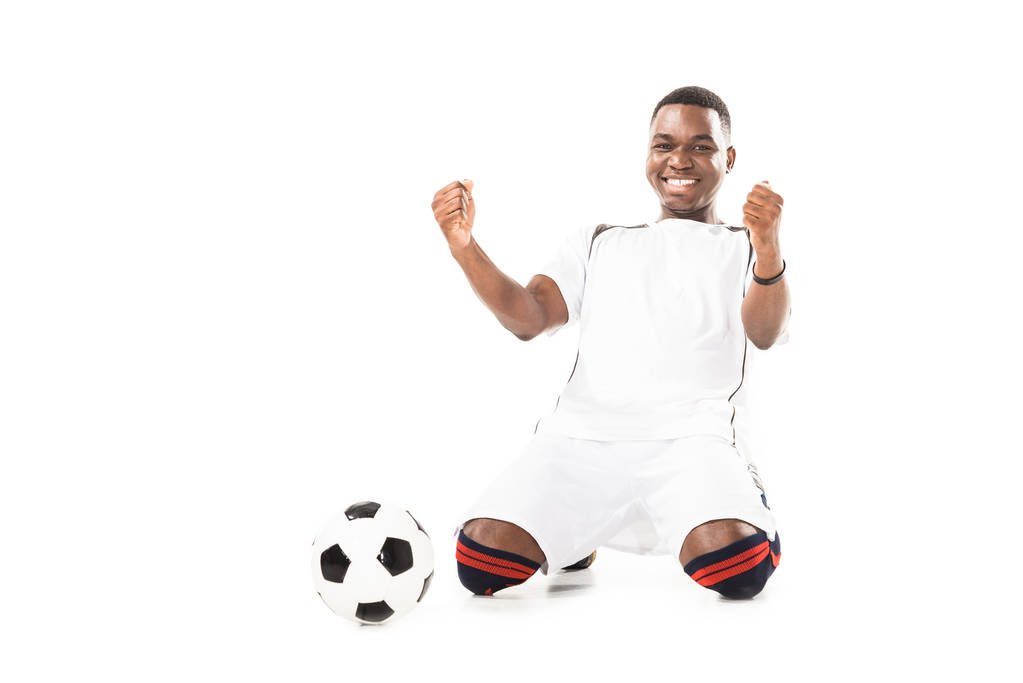 щасливий молодий афроамериканський футболіст тріумфуючий і тремтячий кулаки ізольовані на білому
 - Фото, зображення
