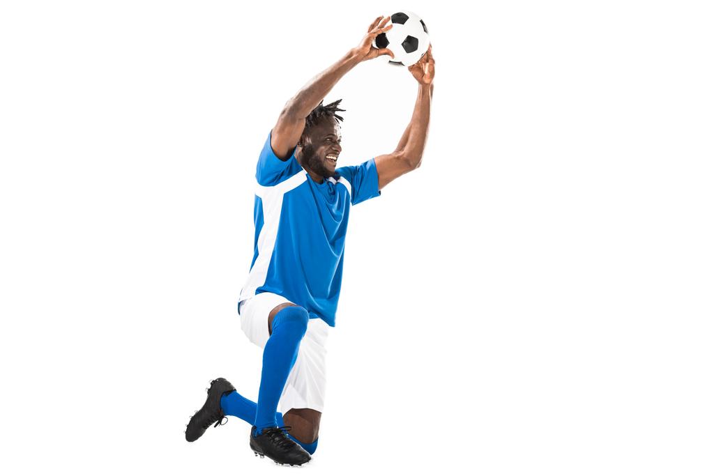 happy african american sportsman kneeling and holding soccer ball isolated on white - Photo, Image