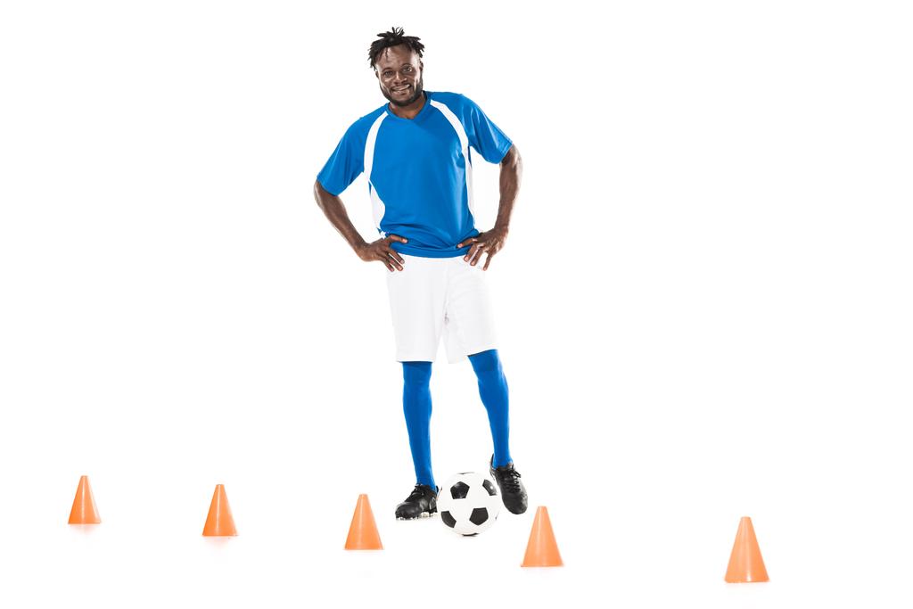 happy young african american soccer player training with ball and marker cones isolated on white  - Photo, Image