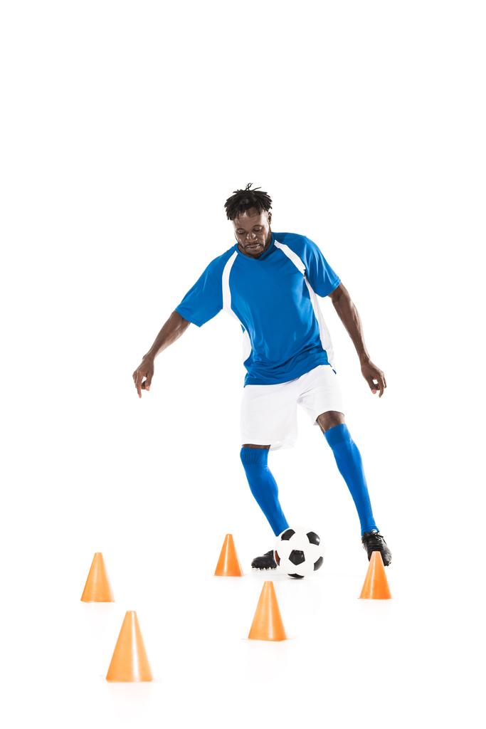 jovem esportista afro-americano treinando com bola de futebol e cones marcadores isolados em branco
  - Foto, Imagem