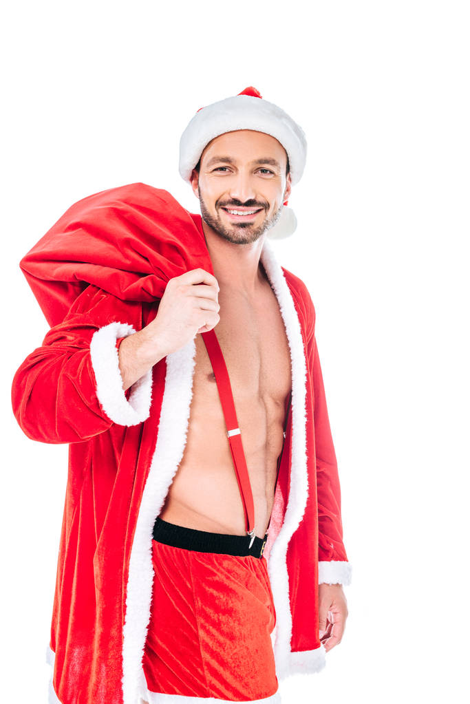 musculoso hombre sonriente en traje de santa claus con saco de Navidad aislado sobre fondo blanco
 - Foto, imagen
