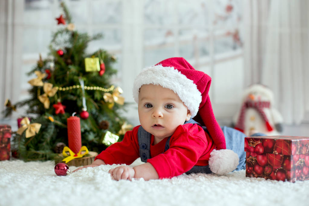 Portrait of newborn baby in Santa clothes and christmas hat, lying on the ground, winter snow landscape outdoor - Photo, Image
