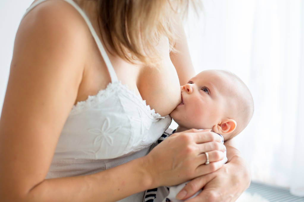 Young mother breastfeeding her newborn baby boy at home - Photo, Image