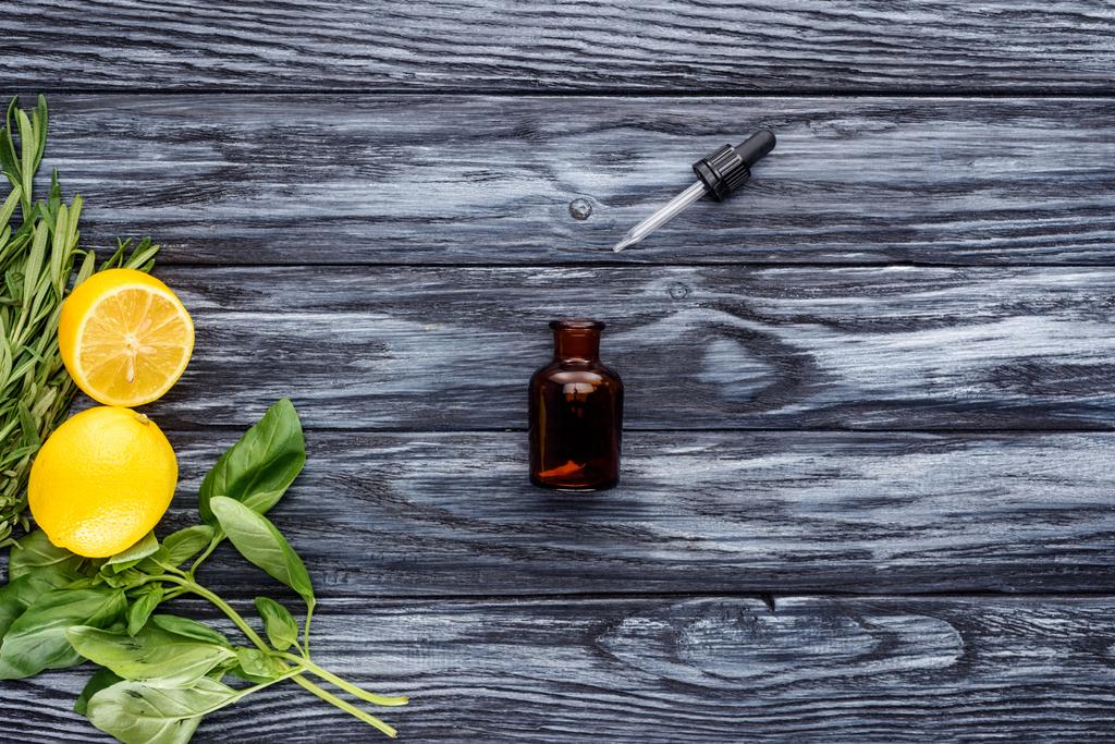vista superior da garrafa de óleo essencial de ervas naturais, conta-gotas e limões na mesa de madeira
 - Foto, Imagem