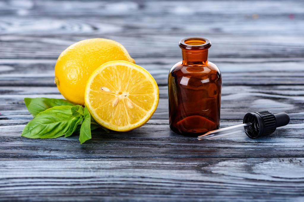 пляшка натуральної трав'яної ефірної олії, піпетки та лимонів на сірій поверхні
 - Фото, зображення