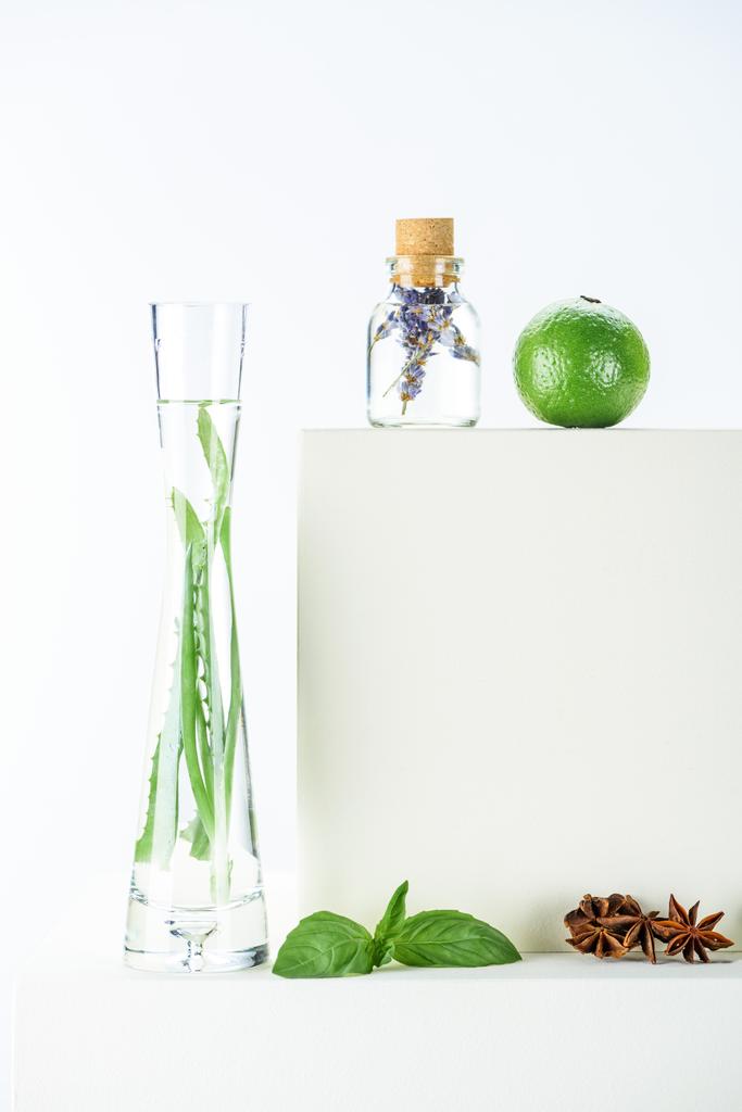 átlátszó üveg és a természetes növényi olajok, a mész, a szegfű, fehér felületre váza  - Fotó, kép