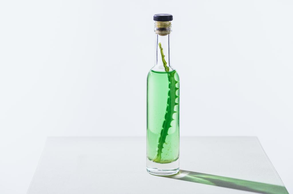 διαφανές μπουκάλι φυσικό φυτικά αιθέρια έλαια με Αλόη Βέρα σε λευκό κύβο - Φωτογραφία, εικόνα
