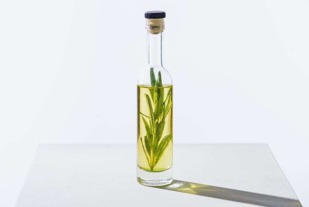 bottle of natural herbal essential yellow oil with twig on white cube - Photo, Image