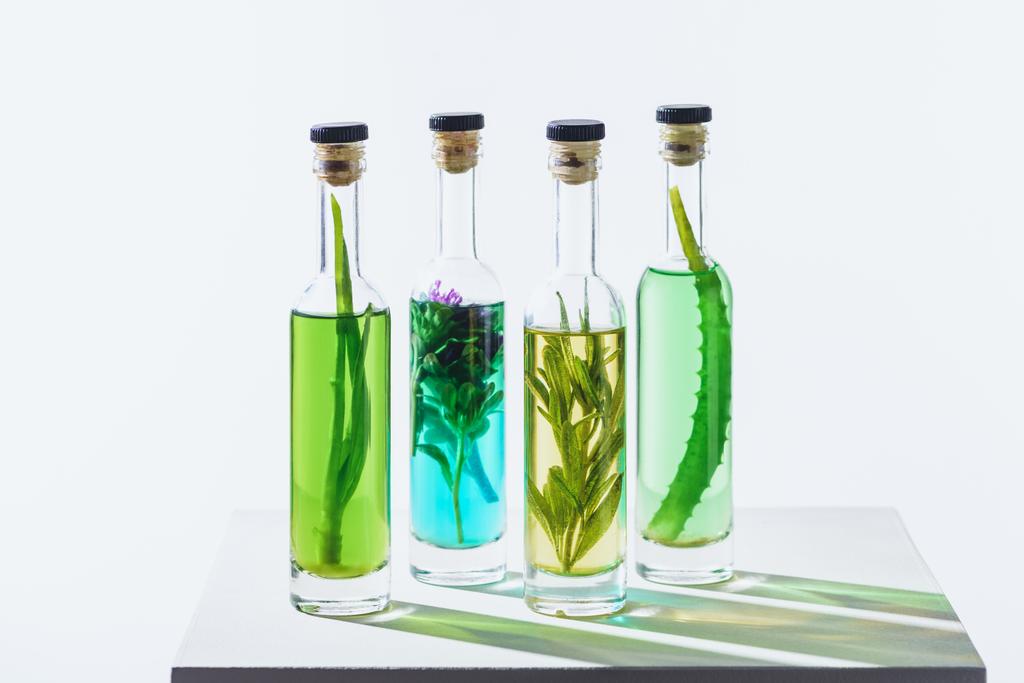 cuatro botellas de aceites esenciales a base de hierbas naturales en cubo blanco
 - Foto, imagen
