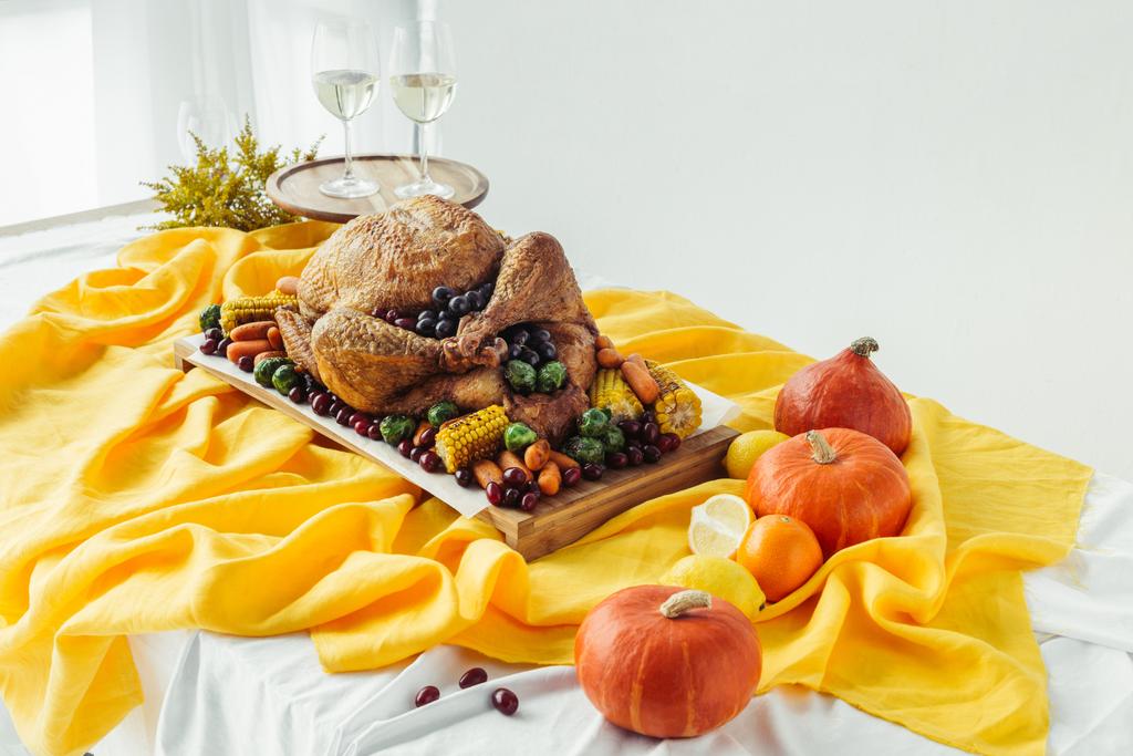 close up view of festive thanksgiving dinner table set with glasses of wine, roasted turkey and vegetables on tabletop with tablecloth - Photo, Image