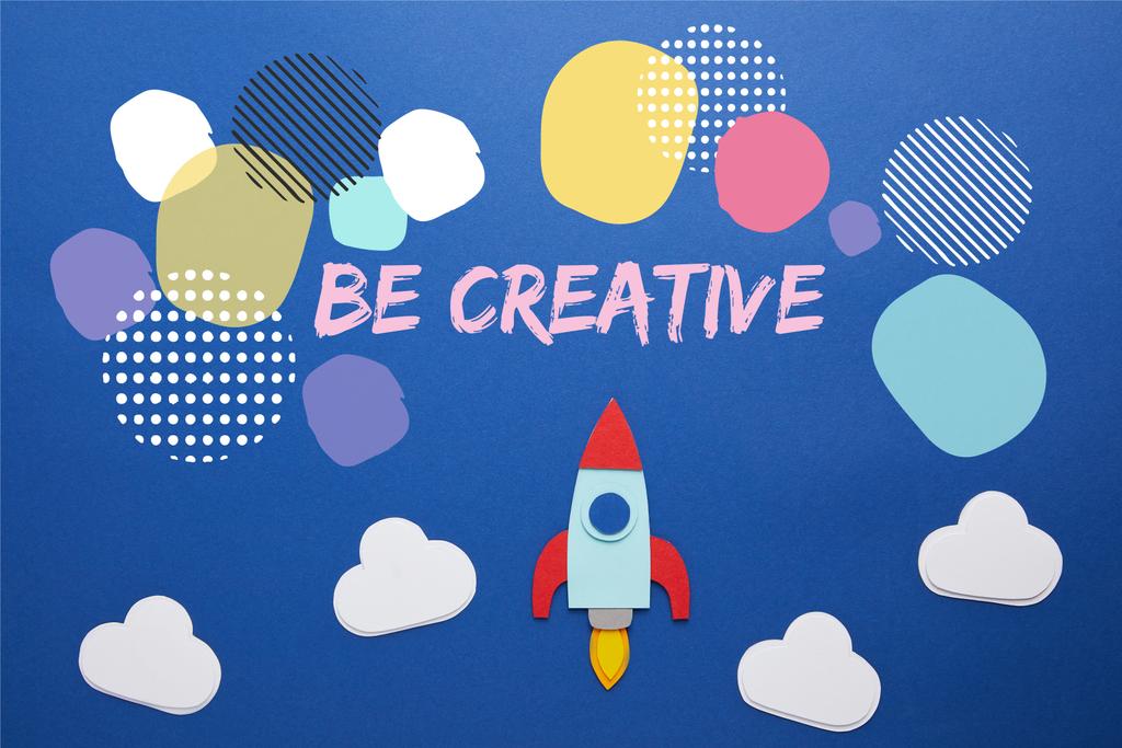 clouds and rocket on blue paper background with "be creative" inspiration - Photo, Image