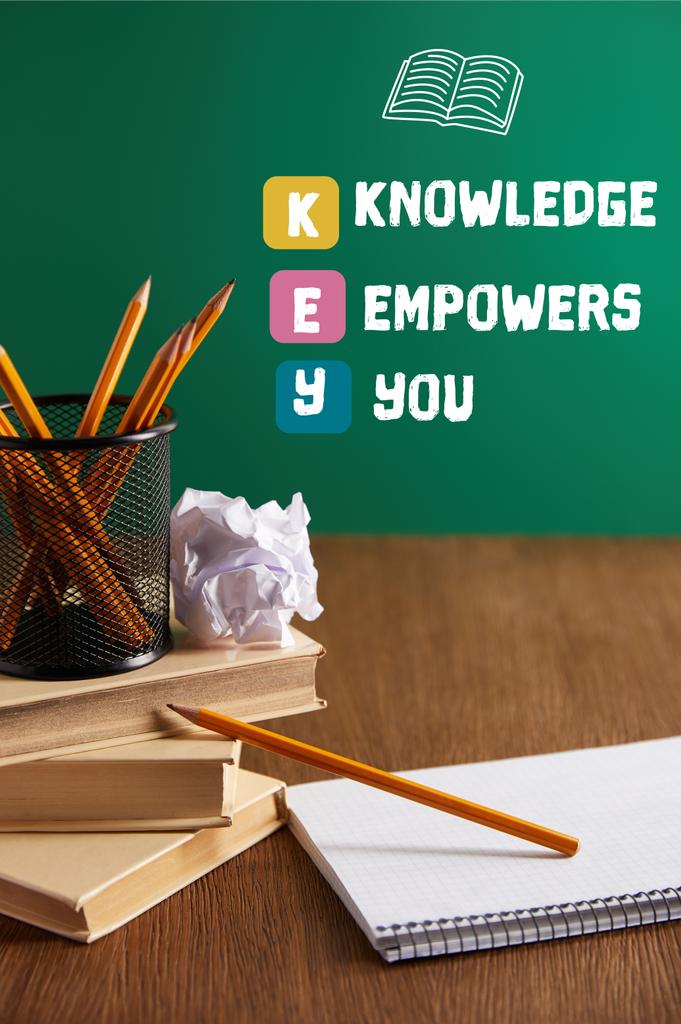 книги, тетрадь, измельченная бумага и карандаши на деревянном столе с надписью "KEY - knowledge empowers you"
 - Фото, изображение