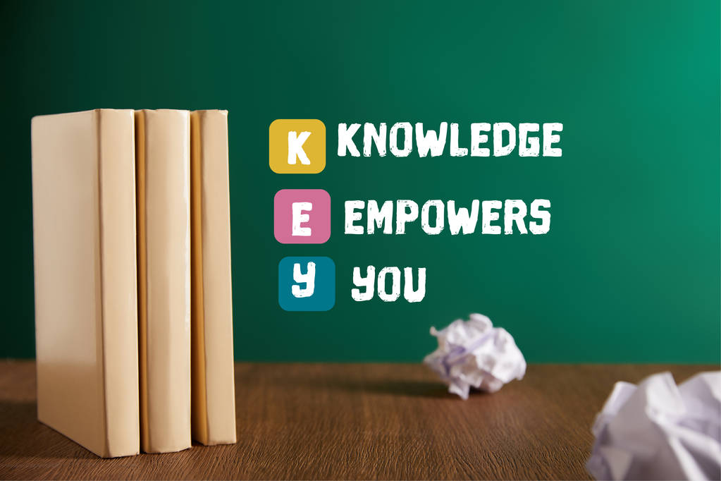 drei Bücher auf Holztisch mit Kreidetafel auf Hintergrund mit der Inspiration "Schlüssel - Wissen macht stark" - Foto, Bild