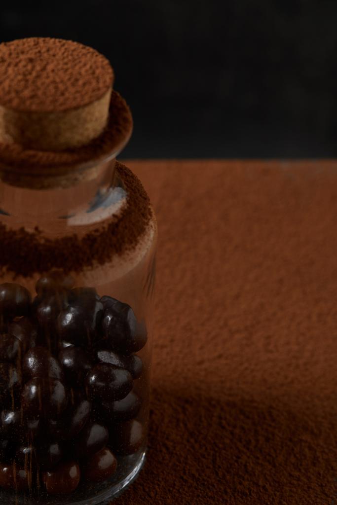Крупный план изысканных шоколадных шариков в стеклянной банке и порошке какао
  - Фото, изображение