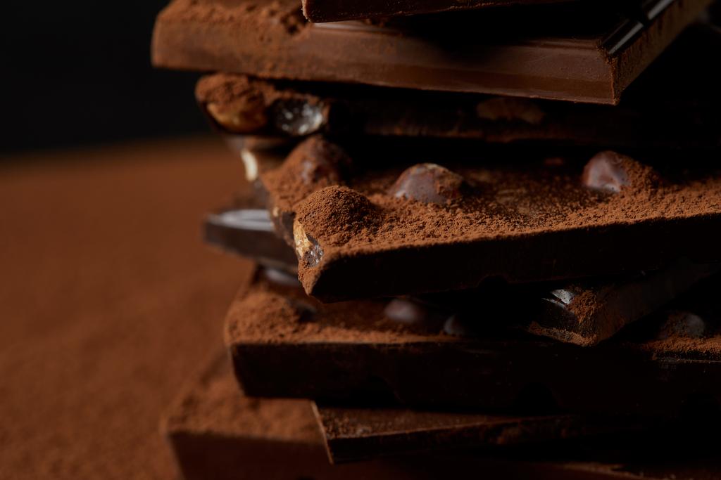 Крупный план вкусных кусочков шоколада с орехами и какао-порошком
 - Фото, изображение