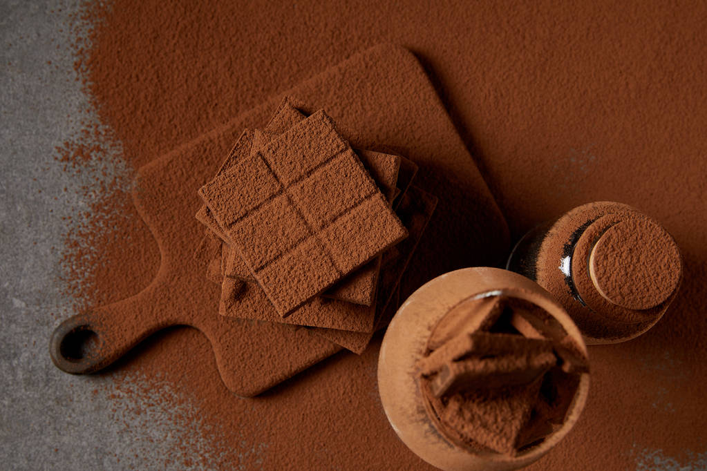 вид сверху на вкусные кусочки шоколада с какао-порошком на доске
 - Фото, изображение