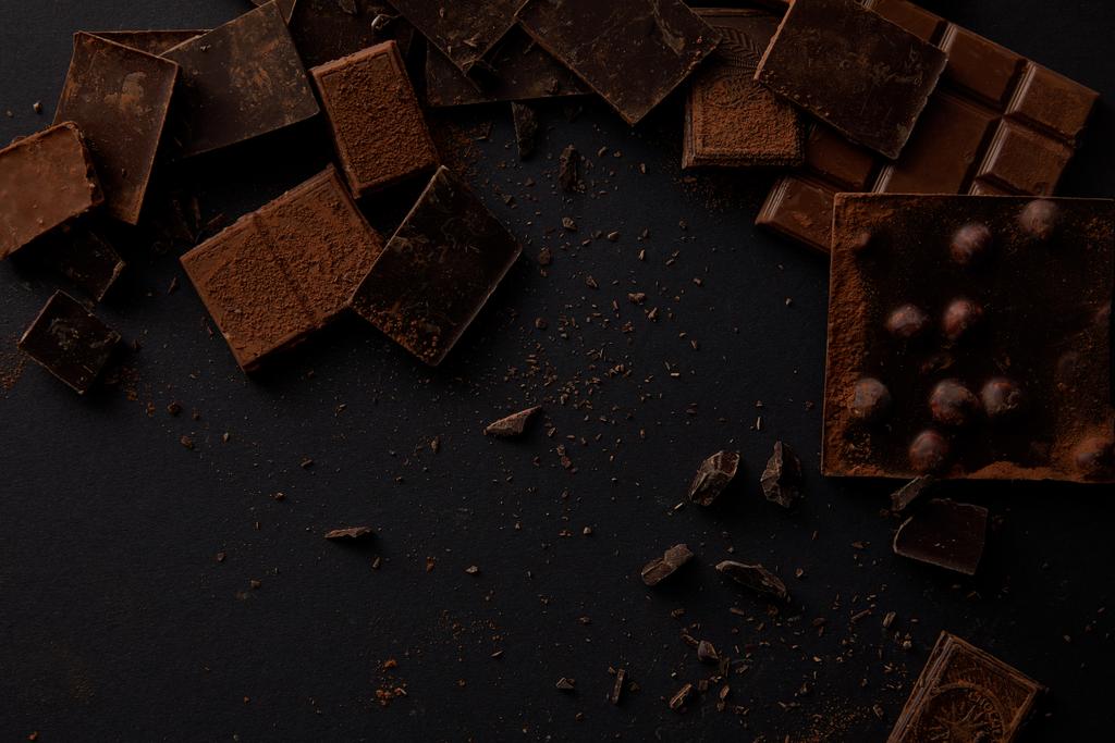 ylhäältä näkymä valikoituja herkullisia suklaapaloja mustalla taustalla
    - Valokuva, kuva