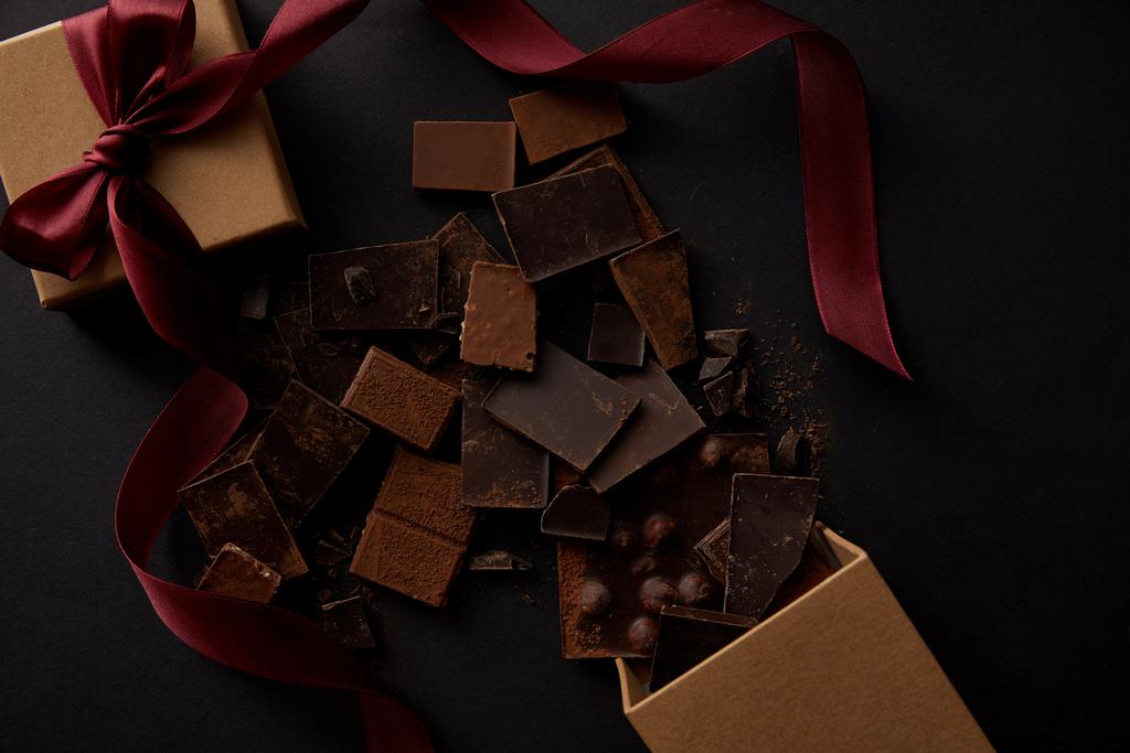 vista superior de deliciosas piezas de chocolate con nueces y caja de regalo en negro
  - Foto, imagen