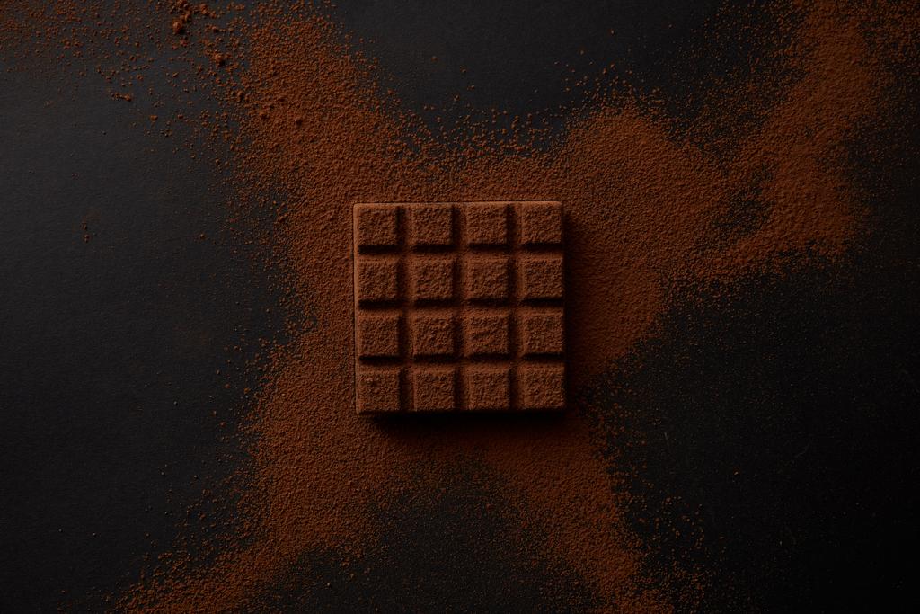 Ansicht von süßer Schokolade und Kakaopulver auf schwarzem Hintergrund - Foto, Bild
