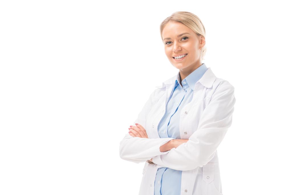 χαρούμενος νεαρός γιατρός θηλυκό με σταυρωμένα τα χέρια βλέπουν τα φωτογραφικών μηχανών που απομονώνονται σε λευκό - Φωτογραφία, εικόνα