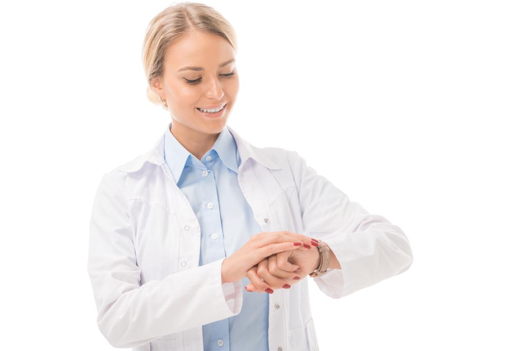 usměvavá mladá lékařka, kontrola času s hodinky izolované na bílém - Fotografie, Obrázek