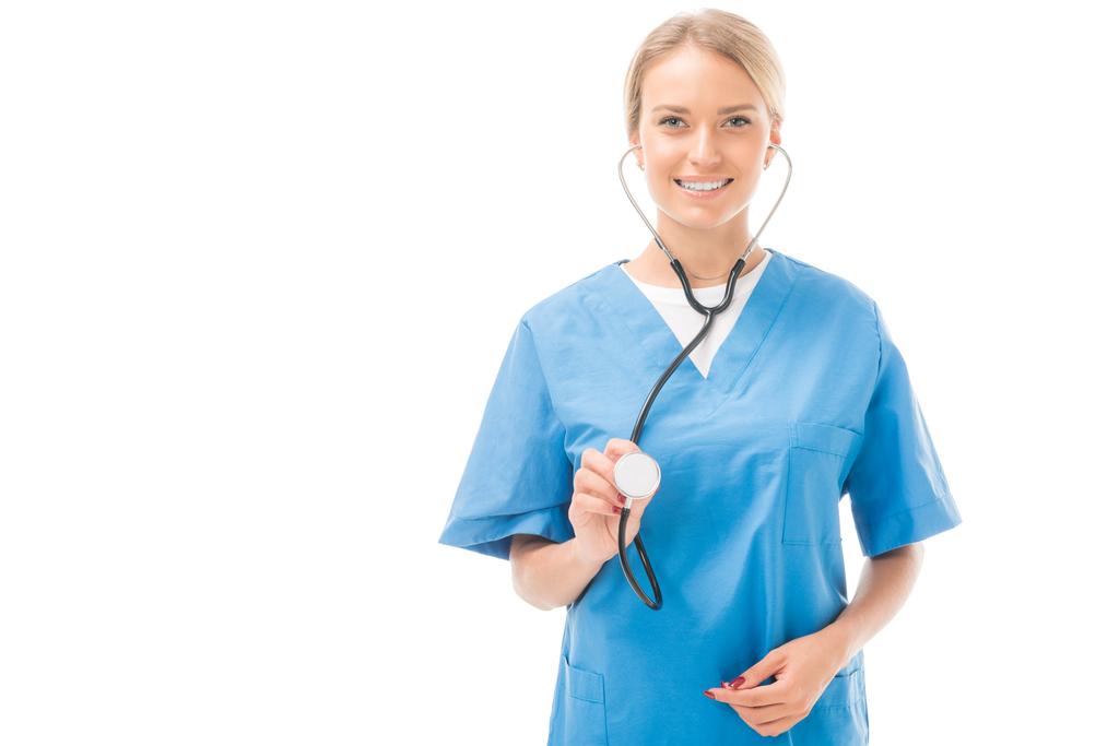 jovem enfermeira sorridente com estetoscópio olhando para câmera isolada em branco
 - Foto, Imagem