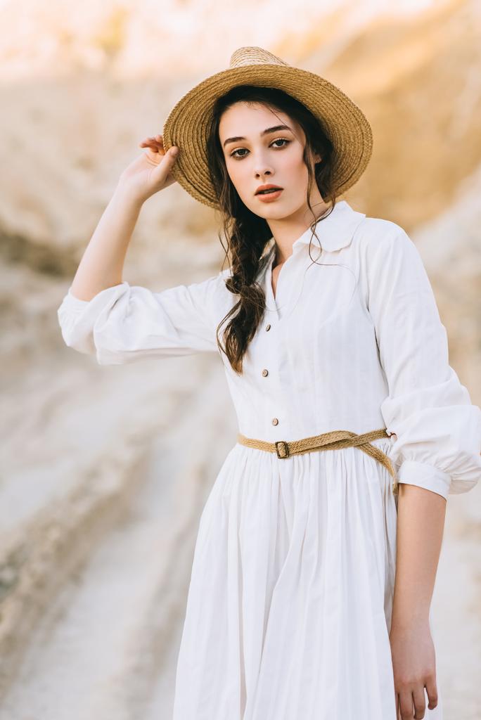 привлекательная стильная девушка в соломенной шляпе, позирующая в песчаном каньоне
 - Фото, изображение